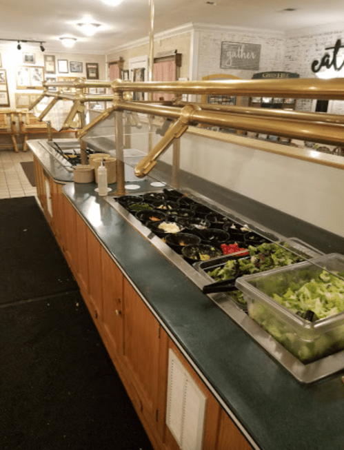 A salad bar with various toppings and ingredients displayed in containers on a countertop.