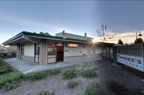 Exterior view of a building with a sign for "Redwood Credit Union" and "Tandee's Restaurant" at sunset.