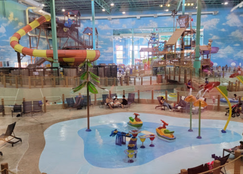 Indoor water park featuring slides, play structures, and a splash area with water features and seating for visitors.