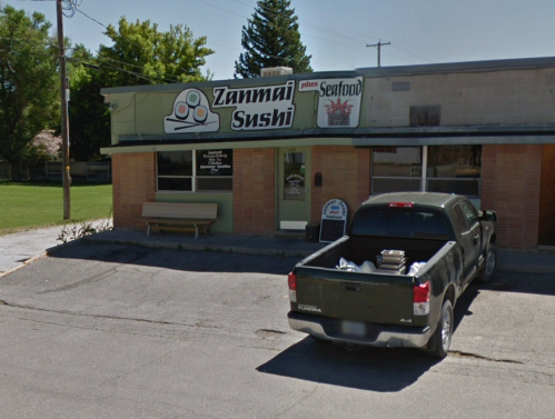 Exterior of Zanmai Sushi restaurant with a green pickup truck parked outside on a sunny day.