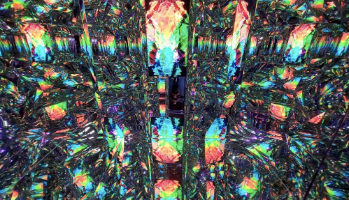 A vibrant, kaleidoscopic pattern of colorful reflections and lights in a mirrored space.