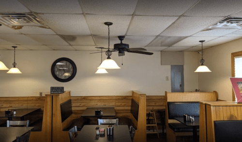 Interior of a casual restaurant featuring wooden booths, ceiling fans, and pendant lighting.