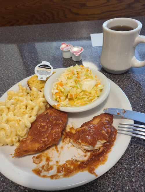 A plate with two pieces of sauced chicken, macaroni and cheese, coleslaw, a biscuit, and a cup of coffee.