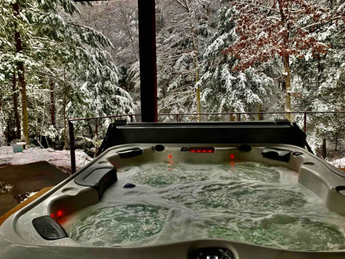 A hot tub with bubbling water, surrounded by snow-covered trees and a winter landscape.