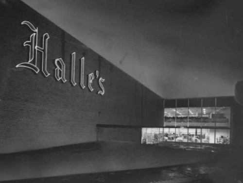 Black and white image of Halle's store exterior at night, featuring illuminated windows and a prominent sign.