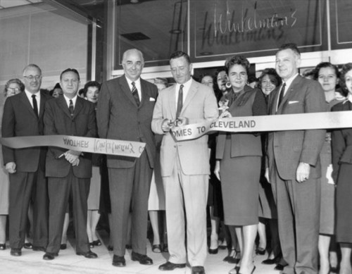 A group of people at a ribbon-cutting ceremony for a new store, smiling and posing for the camera.