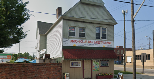 A two-story building with a sign reading "Union Club Bar & Restaurant" and a red awning, surrounded by power lines.