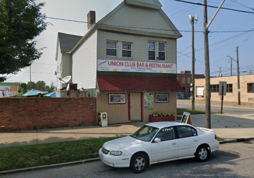 A two-story building with a sign reading "Union Club Bar & Restaurant" and a parked white car in front.