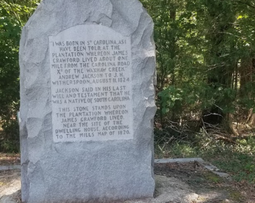 A stone marker with text about Andrew Jackson's connection to a plantation in South Carolina, surrounded by trees.