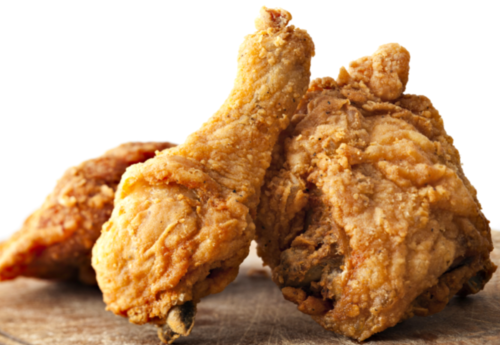 Close-up of crispy, golden-brown fried chicken pieces on a wooden surface.
