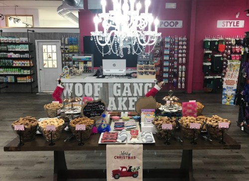 A festive display of treats and decorations in a pet store, featuring a chandelier and a "Merry Christmas" sign.