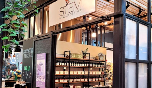 A storefront for "STEM Handmade Soap" featuring shelves of products and a welcoming garden-themed display.