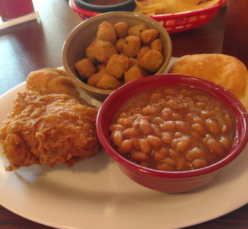 A plate featuring fried chicken, baked beans, fried okra, and a biscuit.