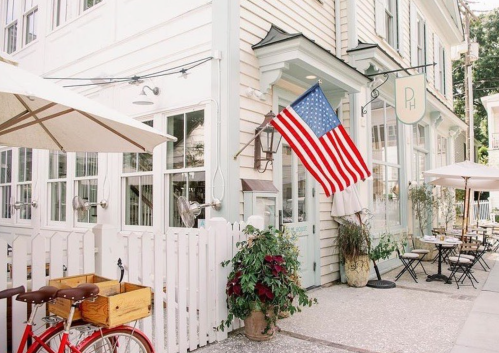 A charming café with an American flag, outdoor seating, and a red bicycle parked nearby.