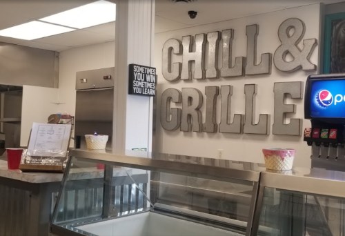 Interior of a restaurant with "Chill & Grille" sign, soda fountain, and menu on display.