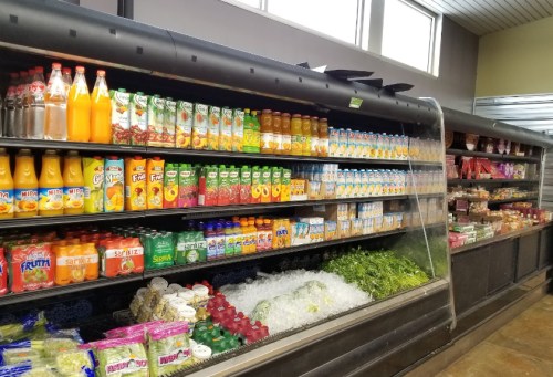 A grocery store display featuring various juices, soft drinks, and fresh produce on ice.