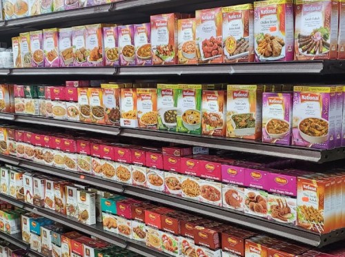 A grocery store shelf filled with various packaged meal kits and spices in colorful boxes.