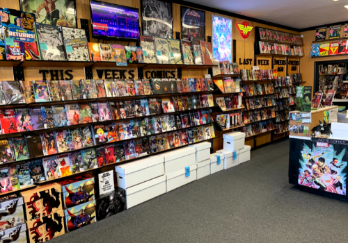 A vibrant comic book store with shelves full of comics, a TV, and a display counter featuring superhero artwork.