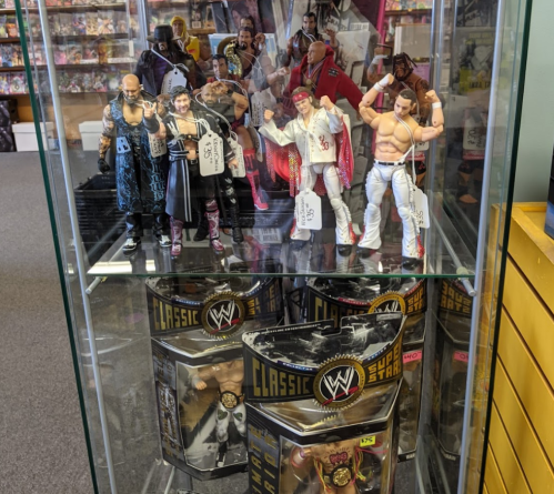A display case featuring various WWE action figures, including wrestlers in colorful outfits and accessories.
