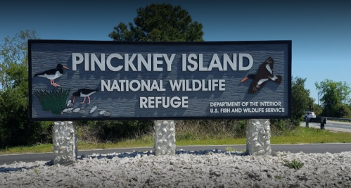 Sign for Pinckney Island National Wildlife Refuge, featuring birds and natural scenery.