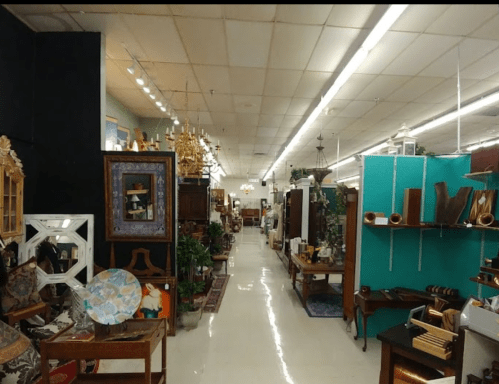 A spacious antique store aisle lined with various vintage furniture and decor items.