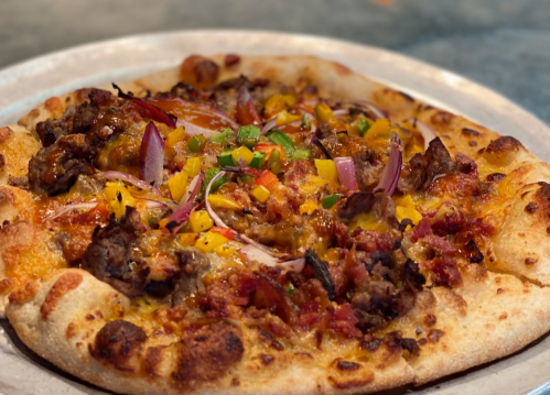 A delicious pizza topped with meat, cheese, colorful peppers, and onions on a golden crust.