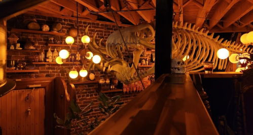 A cozy interior featuring a large fish skeleton, warm lighting, and rustic decor against a brick wall.