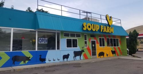 Colorful exterior of "Soup Farm" with animal silhouettes on the wall and an "OPEN" sign in the window.