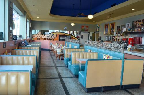 A retro diner interior with teal and beige booths, tables, and vintage decor, creating a nostalgic atmosphere.