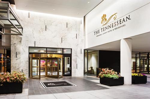 Entrance of The Tennessean hotel, featuring a revolving door and elegant signage, surrounded by planters and modern architecture.