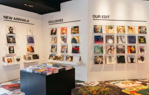 A modern display of vinyl records on white walls, featuring sections for new arrivals, exclusives, and curated edits.