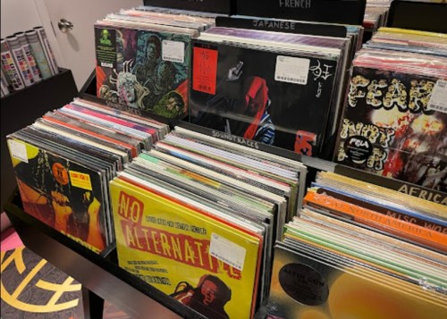 A display of various vinyl records organized by genre, featuring colorful album covers and price tags.