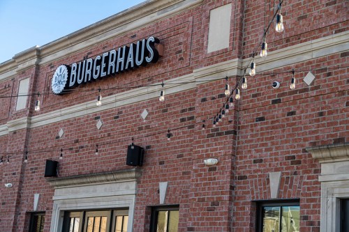 Exterior of a brick building with a sign reading "BURGERHAUS" and decorative string lights above.
