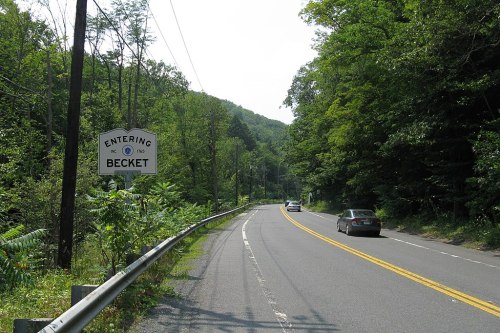 A scenic road with a sign reading "Entering Becket" surrounded by lush greenery and trees.