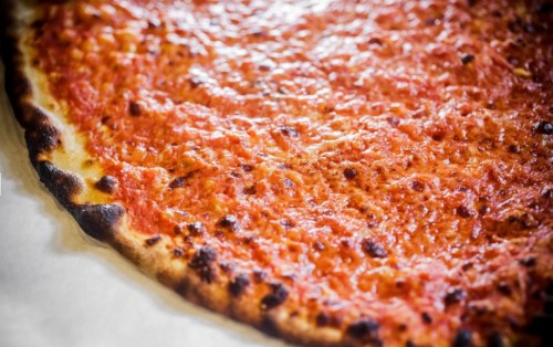 Close-up of a freshly baked pizza with a golden crust and a rich, red tomato sauce topping.
