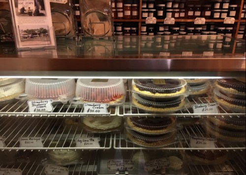 Display case filled with various pies and desserts, each labeled with prices.