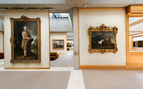 Interior of an art gallery featuring large framed paintings on the walls and a minimalist design.