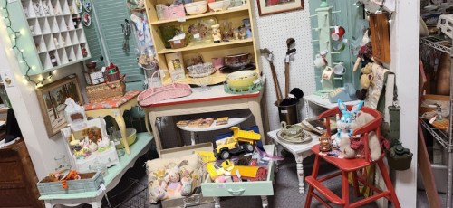 A cozy vintage shop display featuring colorful decor, antiques, and various collectibles on shelves and tables.