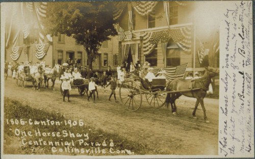 A historic parade featuring a horse-drawn carriage and people in period clothing, decorated with flags and bunting.