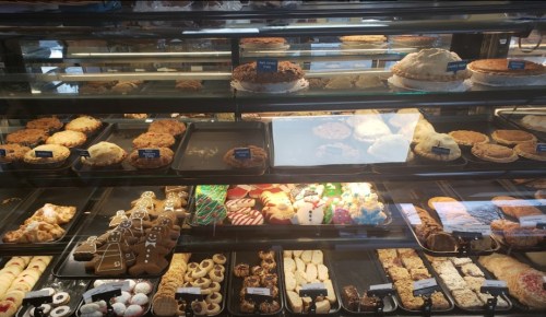 A display case filled with various baked goods, including cookies, pies, and festive treats.