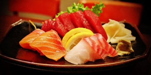 A platter of assorted sushi, featuring slices of salmon, tuna, and garnishes like lemon and wasabi.