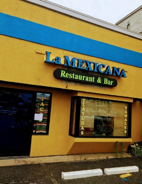 Sign for "La Mexicana Restaurant & Bar" with colorful exterior and window displays of tacos, tlacoyos, and tamales.