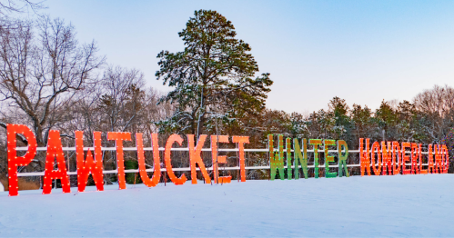 Colorful illuminated letters spell "Pawtucket Winter Wonderland" against a snowy landscape and trees.