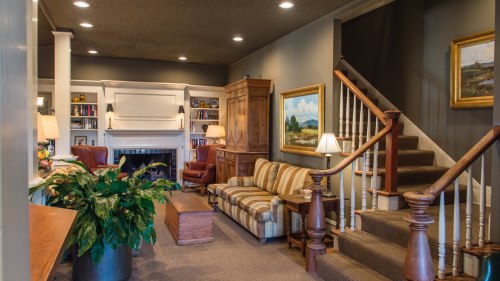 Cozy living room with a striped sofa, wooden furniture, a fireplace, and a staircase leading to an upper level.