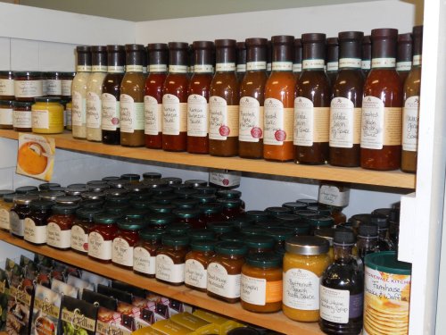 Shelves filled with various jars and bottles of sauces, jams, and preserves, all labeled neatly.