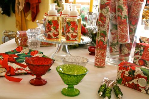 A festive table display featuring decorative soaps, colorful glass bowls, and holiday-themed wrapping paper.