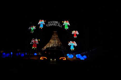 A festive display featuring illuminated angels and a tree, with the words "Goodwill Toward All" against a dark background.