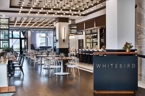 Modern restaurant interior with white and black decor, featuring tables, chairs, and a sign that reads "WHITEBIRD."