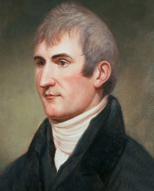 Portrait of a man with light hair and a serious expression, wearing a dark coat and white collar.
