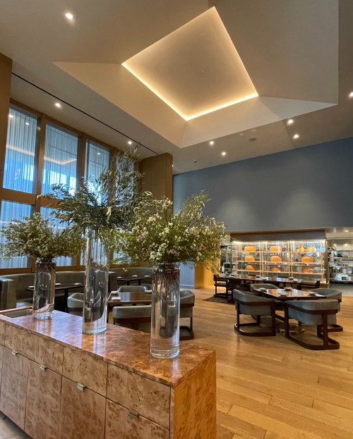 Modern restaurant interior featuring elegant floral arrangements, wooden flooring, and stylish seating.